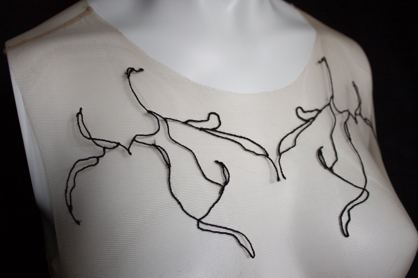 White garment with black embroidered designs on a black background