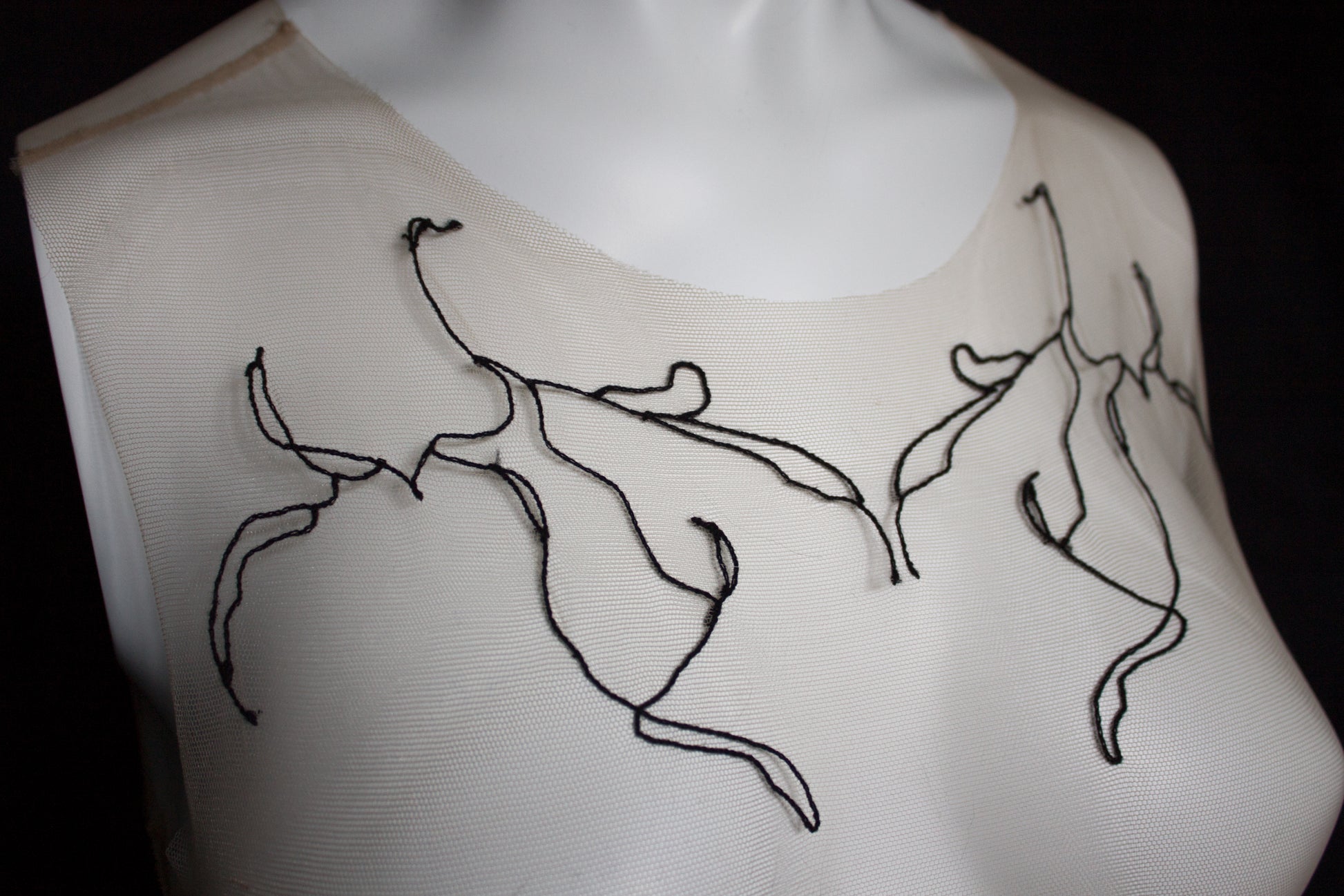 White garment with black embroidered designs on a black background