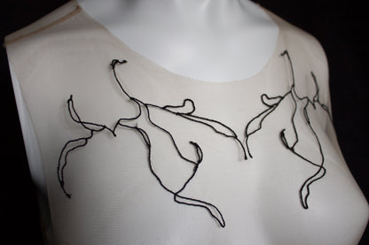 White garment with black embroidered designs on a black background