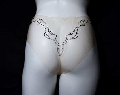 Mannequin wearing a beige garment with black abstract designs on a black background