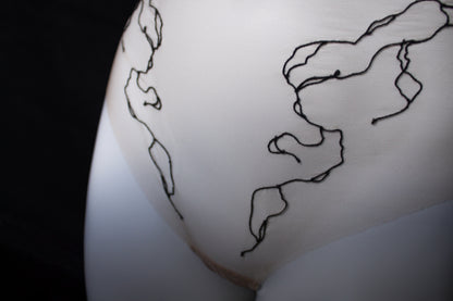 Close-up of a beige garment on a mannequin with a black line embroidery