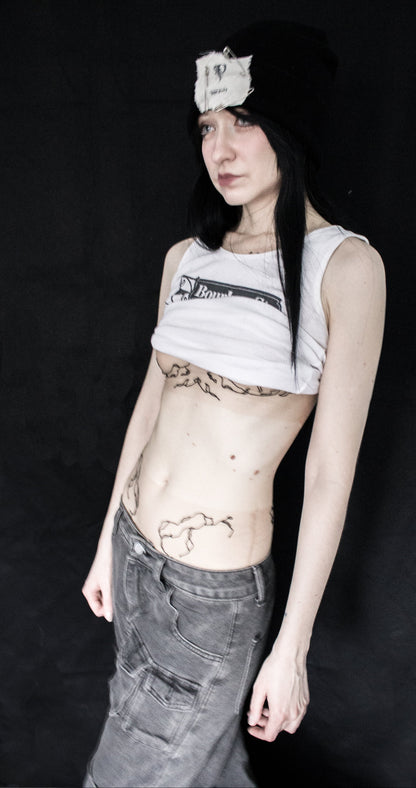 Person wearing a sleeveless top with a brand logo and dark pants against a black background