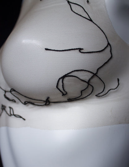 Close-up of a tattoo on a person's front with a black outline design.